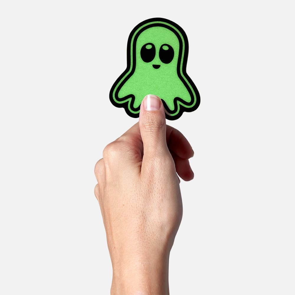 A hand holding a glow in the dark ghost shaped sticker printed by StickerGiant