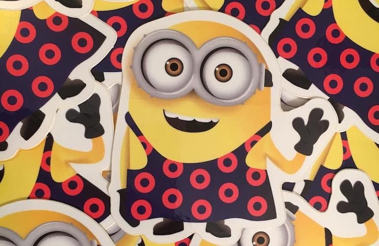A group of custom die cut stickers featuring a cartoon yellow character with goggles wearing a dark blue outfit patterned with bright red donut shaped circles.