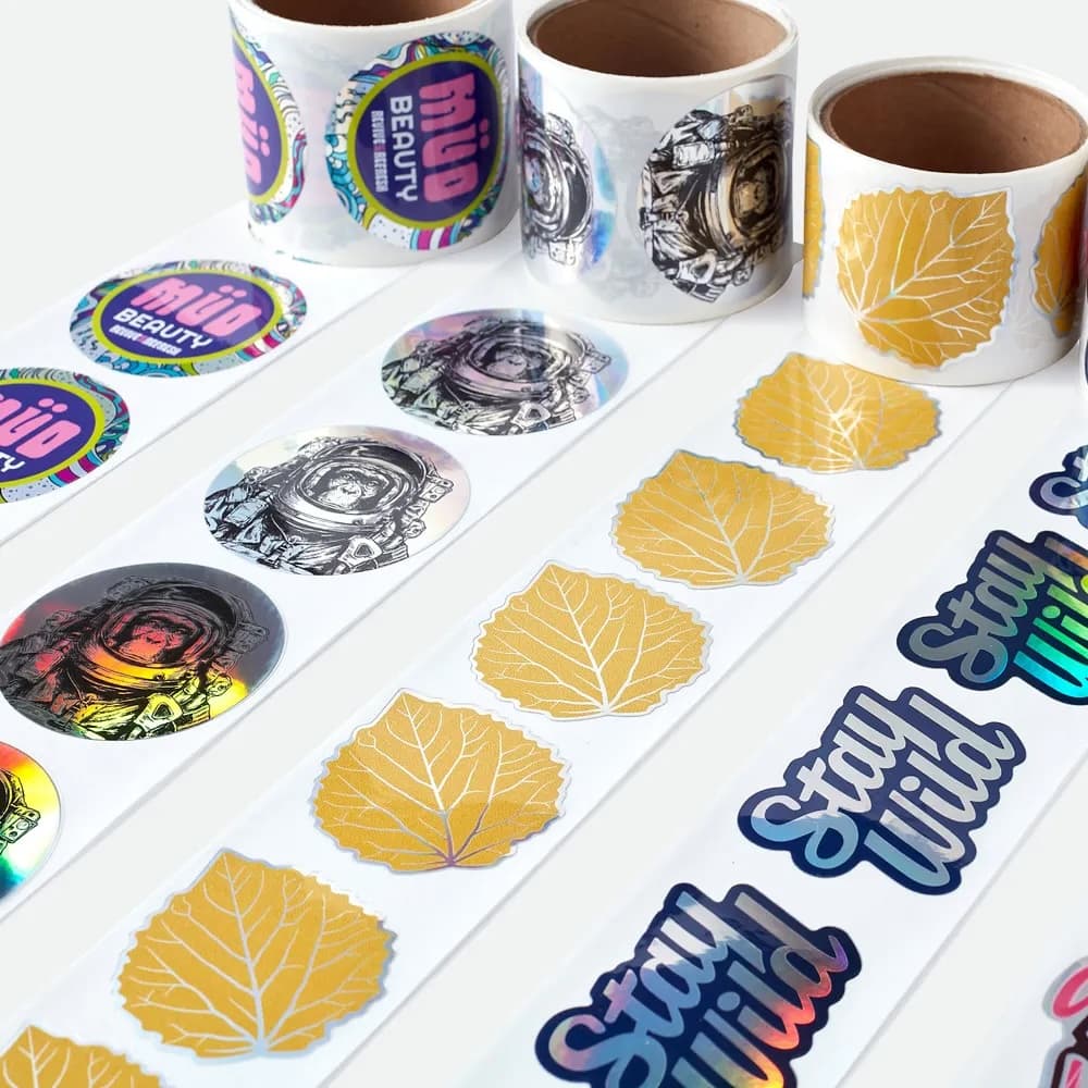 Custom kiss cut holographic stickers on rolls with rainbow metallic finish and easy-peel backing.