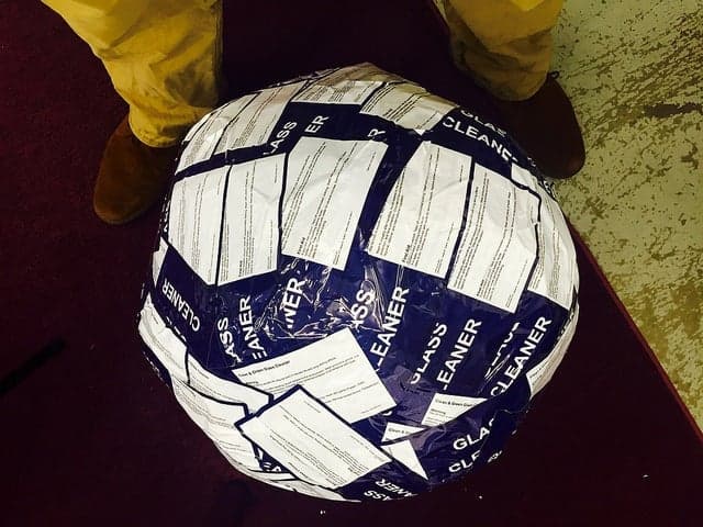 Top down view of a partially built sticker ball covered in overlapping product stickers.