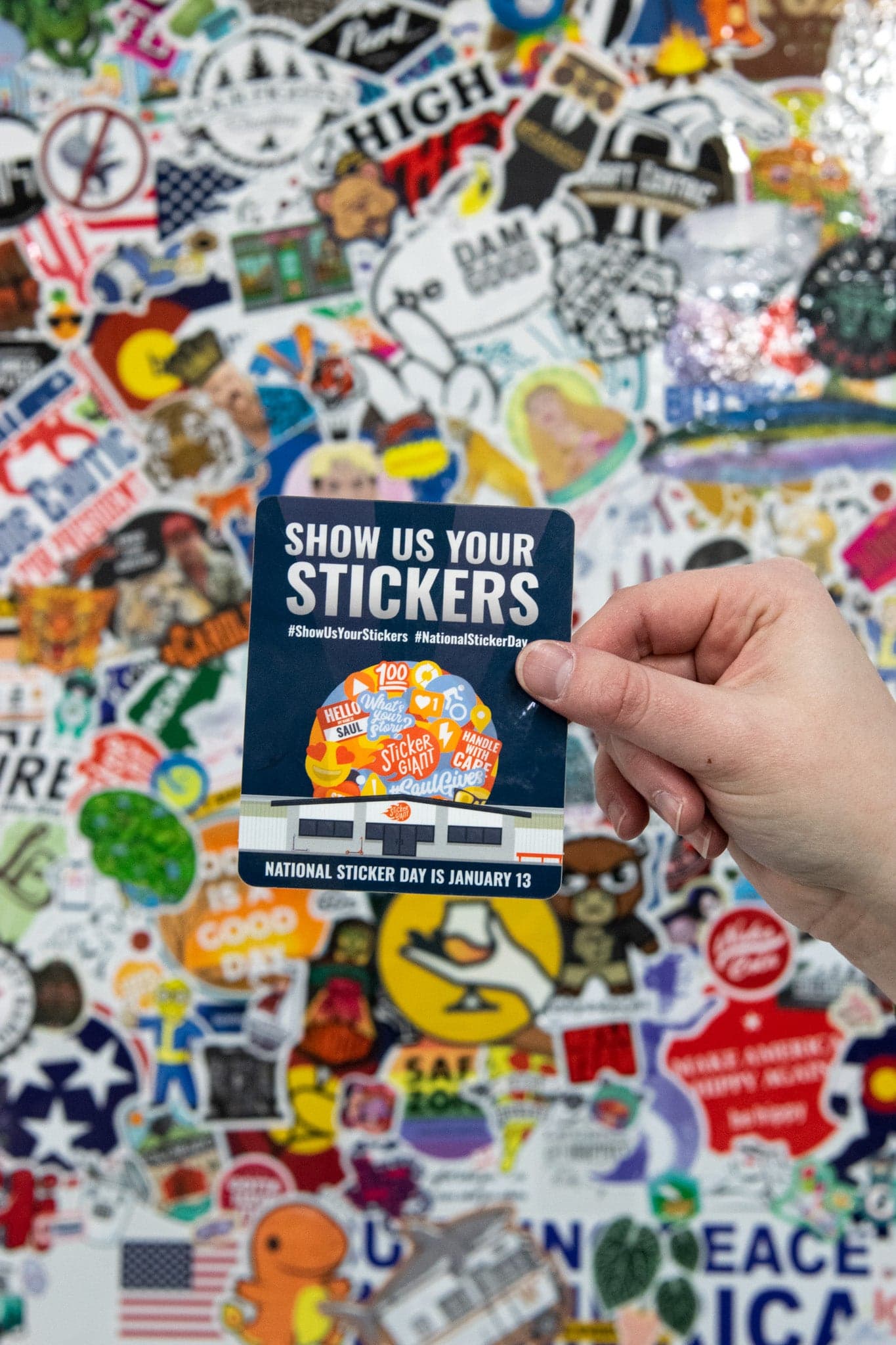 A background of stickers on a wall with a featured sticker that says Show Us Your Stickers