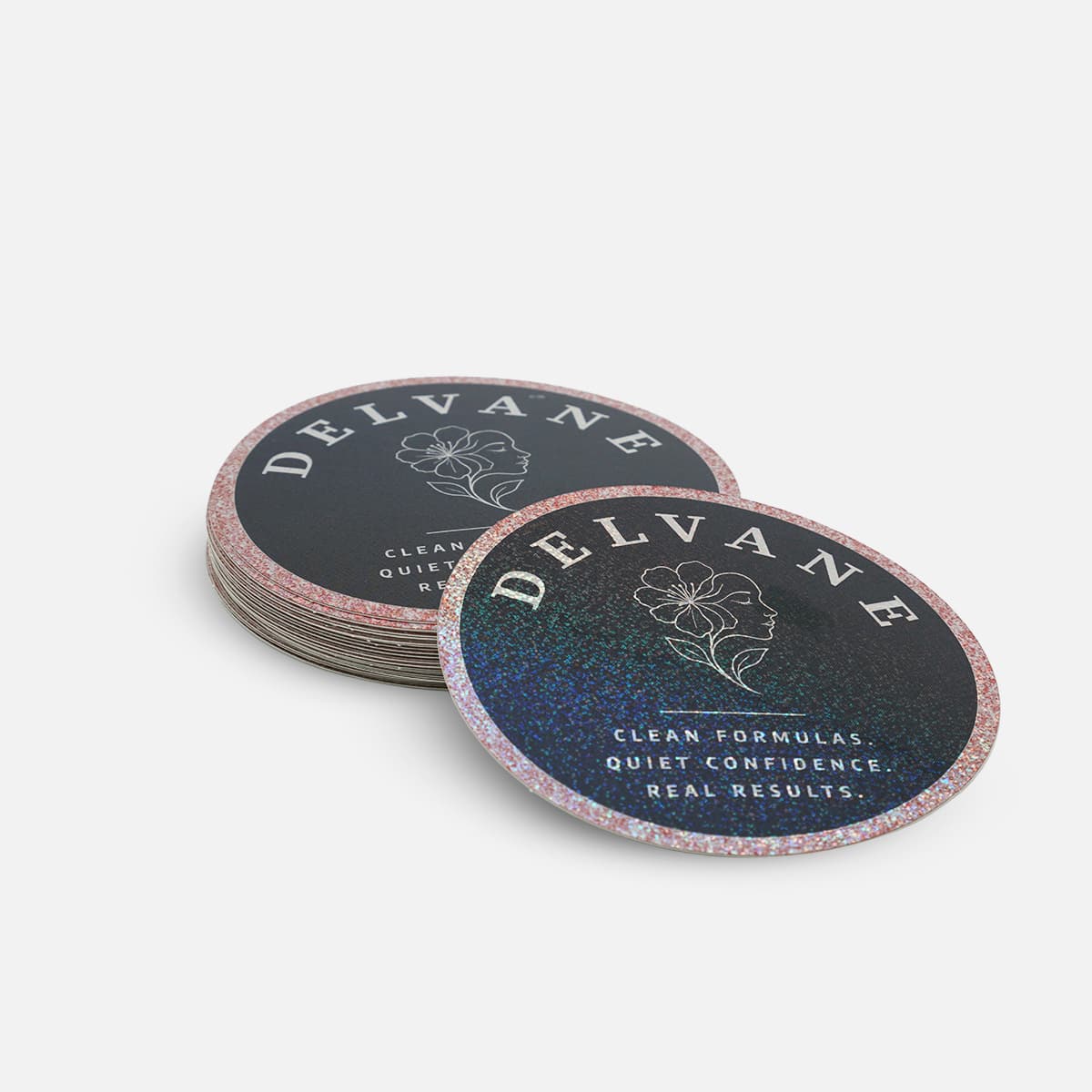Stack of custom round glitter stickers featuring the Delvane logo with holographic glitter effects and premium branding design.