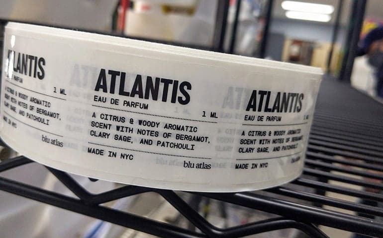 Roll of Clear Labels for a perfume product with black typography.