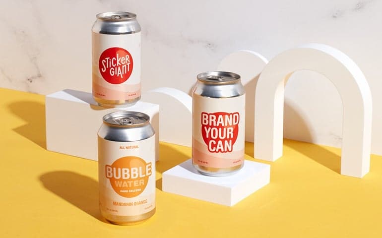 Custom labeled beverage cans displayed on white stands.
