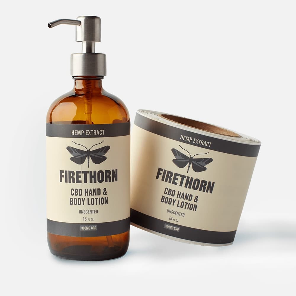 Custom matte paper lotion label on an amber bottle beside a label roll.